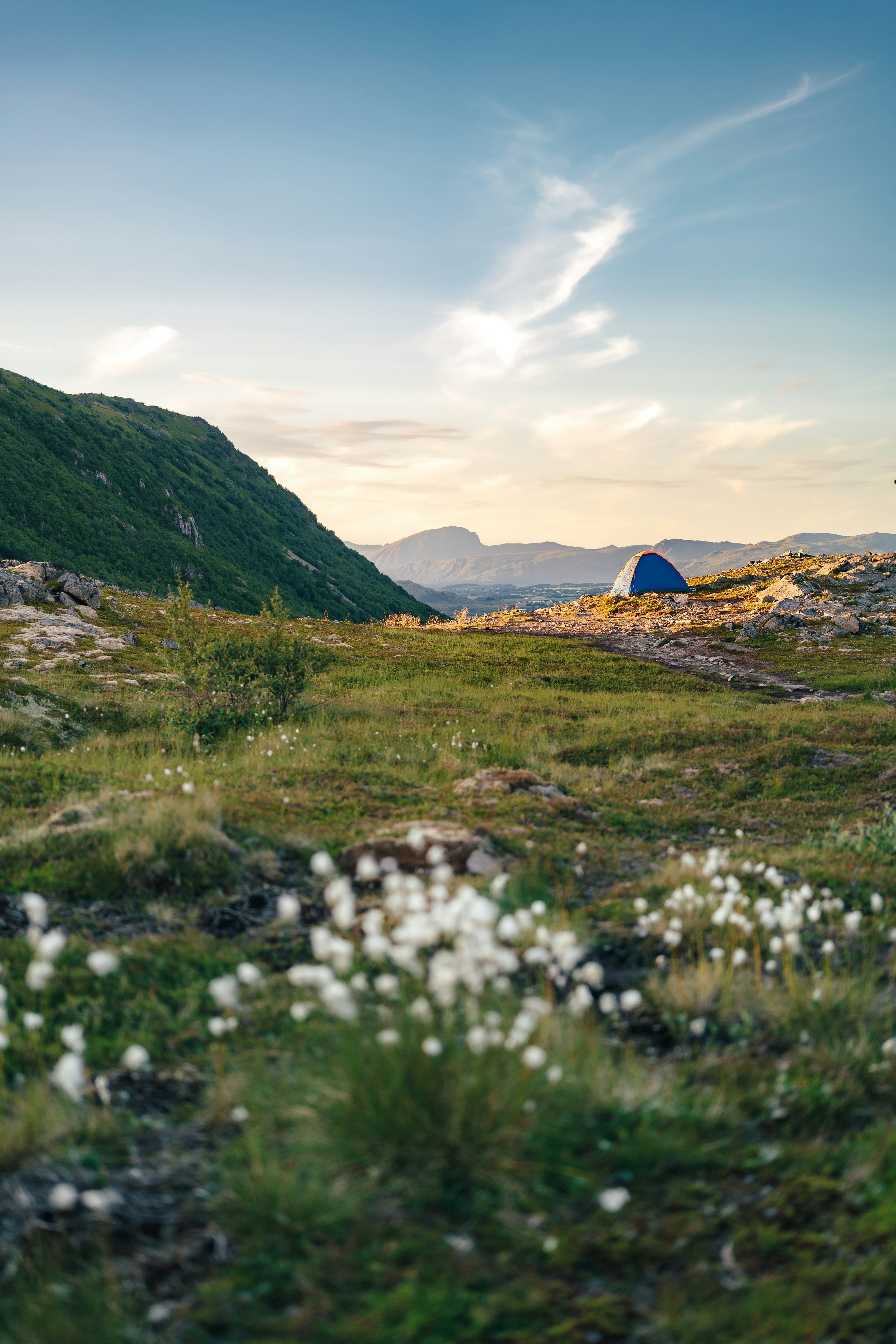 Tent on a green mountain ridge at sunset